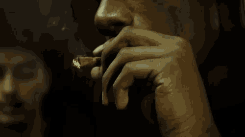 a close up of a man smoking a cigar with smoke coming out of his mouth