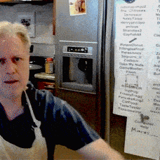 a man in an apron stands in front of a refrigerator with a menu on the door