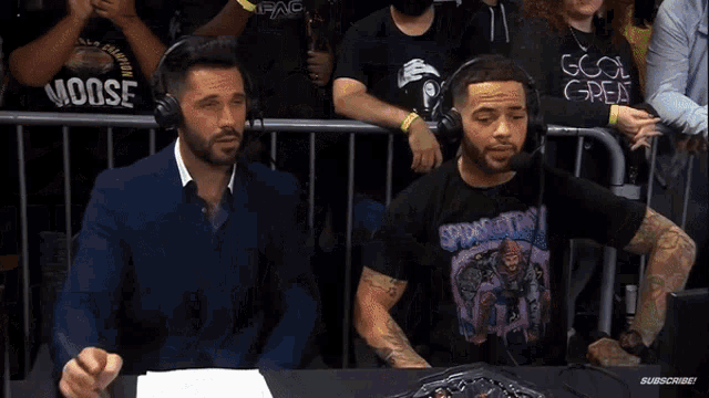 a man wearing a spider-man t-shirt is sitting at a table with two other men .