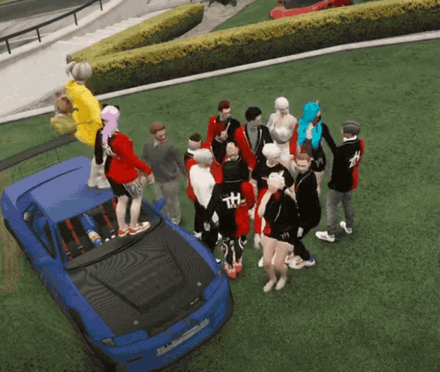 a group of people are gathered around a blue car with the letter th on the back
