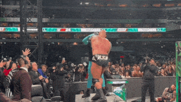a wrestler is being lifted in the air by another wrestler in front of a crowd that is watching