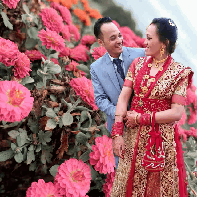 a man in a suit and tie stands next to a woman in a red dress