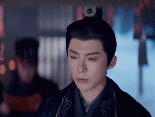 a young man with a crown on his head looks at the camera