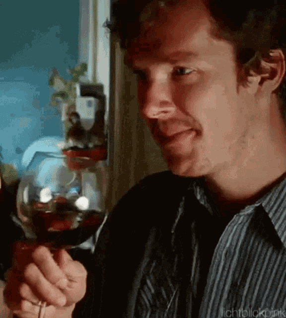 a man is holding a glass of wine in his hand .