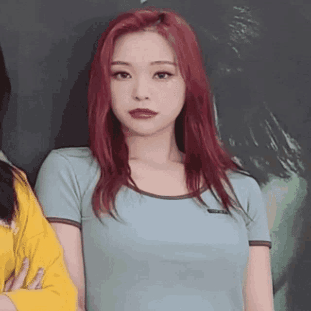 a woman with red hair is wearing a blue t-shirt and a yellow shirt .