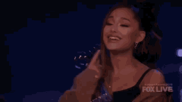 ariana grande is holding a heart shaped object in her hand .