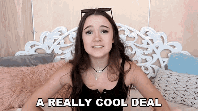 a girl is sitting on a bed with the words a really cool deal written below her