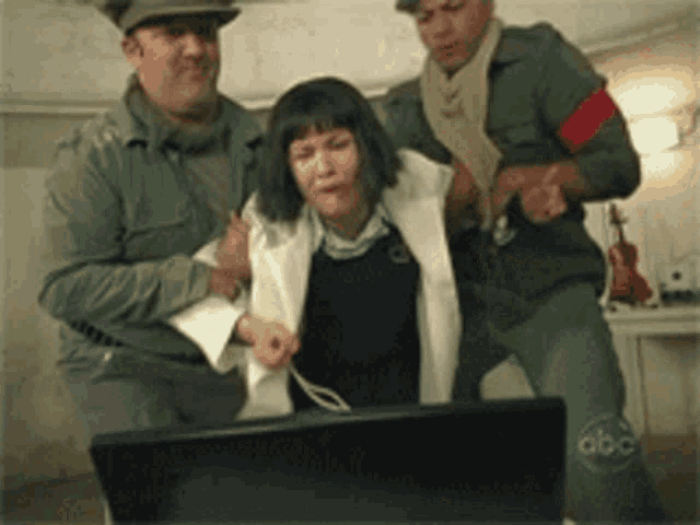 a man in a green uniform is holding a woman in front of a laptop with abc written on it