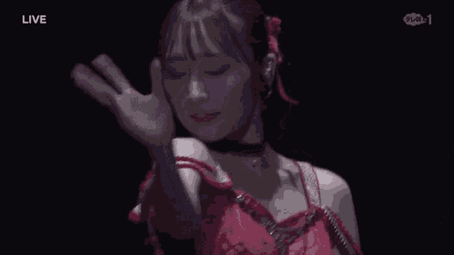 a woman in a red dress is dancing in a dark room with the word live in the corner