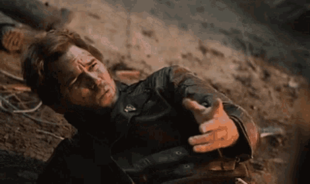 a man in a leather jacket laying on the ground