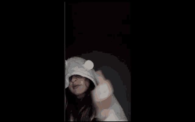 a woman is wearing a white hat with ears on it and giving the middle finger .