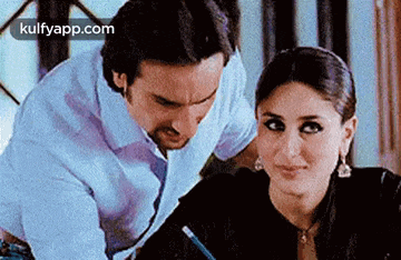 a man and a woman are sitting at a table and looking at each other .