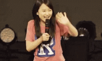 a woman is holding a microphone in her hand and smiling .