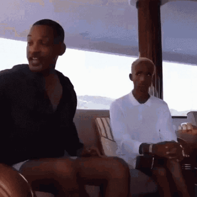 two men are sitting on a boat and one of them is talking to the other .