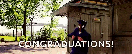 a spiderman in a graduation cap and gown is standing in front of a wooden building .