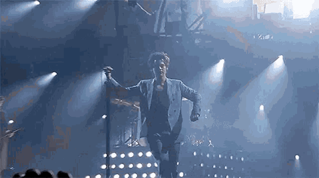 a man in a suit is dancing on a stage while holding a microphone .