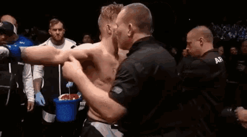a referee is hugging a fighter in a boxing ring .