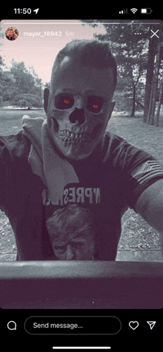 a man wearing a skull mask is taking a selfie on a phone