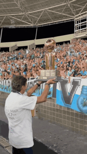 a man holding a trophy in front of a crowd with a banner that says v.