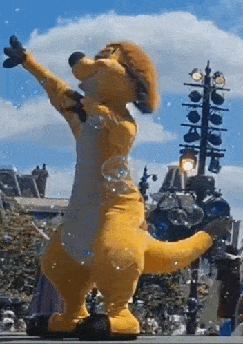 a kangaroo mascot is dancing in front of a crowd while blowing soap bubbles .