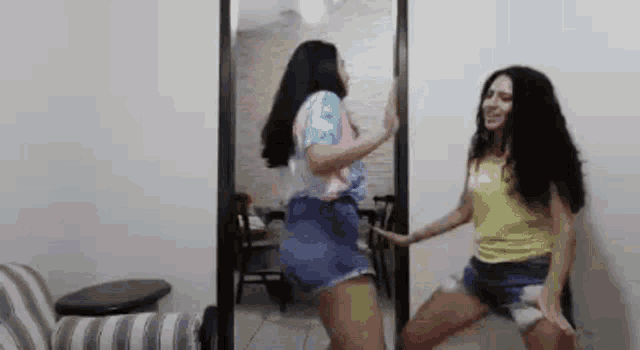 two young women are dancing in front of a mirror .