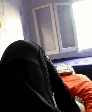 a person laying on a bed in front of a window and a book