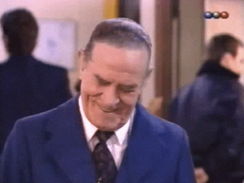 a man in a blue suit and tie is smiling in front of a sign that says 000