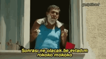 a man with a beard is standing in front of a window and shaving his face .