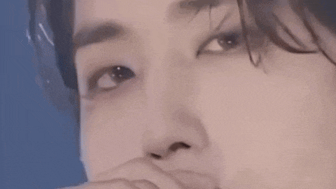 a close up of a person 's face with a hand covering their mouth .