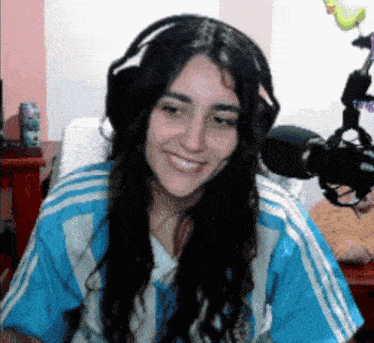 a woman wearing headphones and a blue shirt smiles at the camera