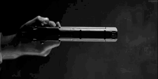 a black and white photo of a person holding a gun that is shooting .