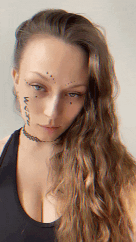 a woman with long hair has a tattoo on her face
