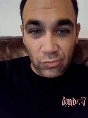 a close up of a man 's face with a black shirt that says bombs on it