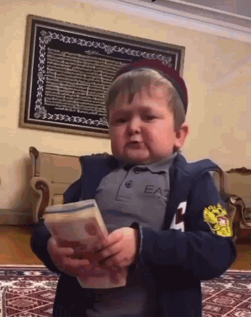 a little boy wearing a ea7 shirt is holding a large stack of money