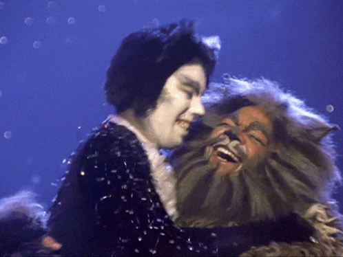 a man in a cat costume is hugging another man in a bearded cat costume