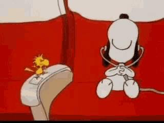 a cartoon of snoopy and woodstock sitting on a red couch with headphones on .