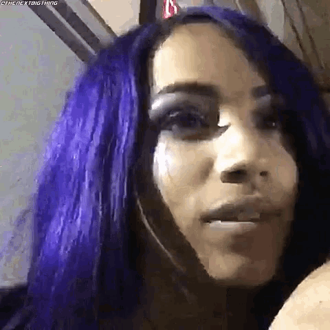 a close up of a woman 's face with purple hair