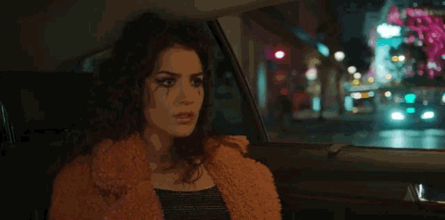 a woman in a fur coat is sitting in the back of a car