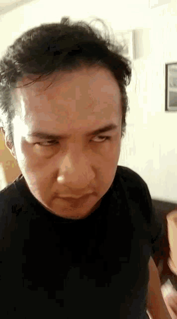 a man in a black shirt is making a funny face while looking at the camera .