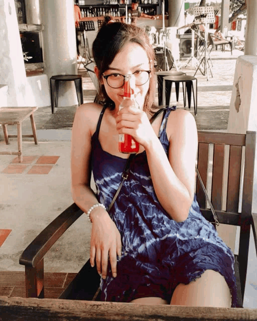 a woman sitting in a chair drinking from a bottle