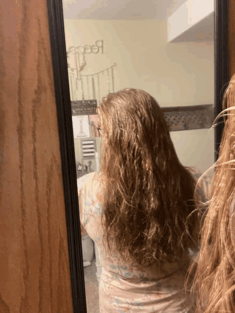 a woman taking a picture of her hair in front of a mirror with the letter b on the wall