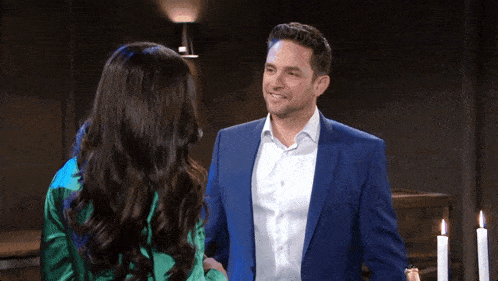 a man in a blue suit shakes hands with a woman in a green shirt