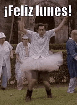 a man is wearing a tutu and dancing in a park with a group of people .