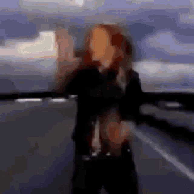 a blurry picture of a woman with red hair standing on a street .