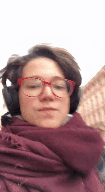 a woman wearing red glasses and headphones is wearing a purple scarf around her neck