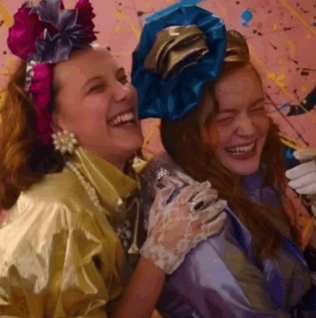 two women are standing next to each other and laughing .