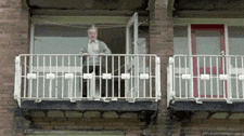 a man is standing on a balcony with a red door