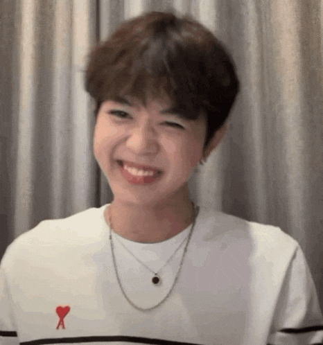 a young man wearing a white shirt with a red heart on it is smiling