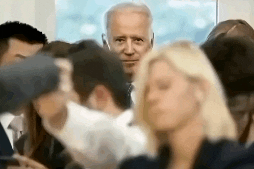 a blurry picture of a man in a suit and tie surrounded by people
