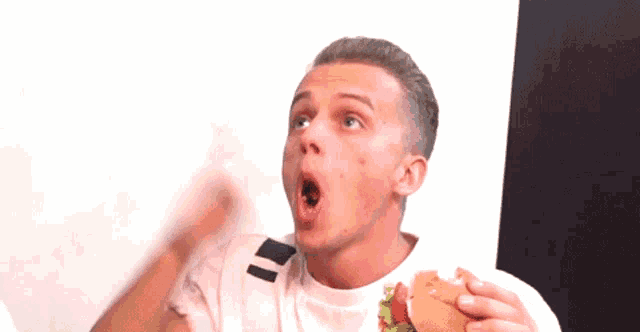 a young man eating a hamburger with his mouth open